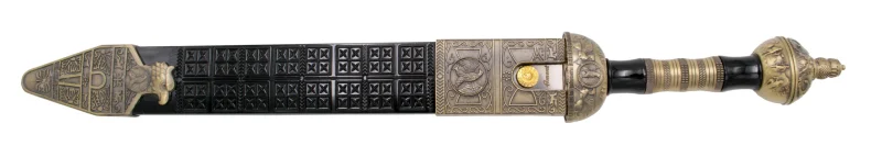 Daga Romana S3327, el pomo está acabado en bronce antiguo y el mango en plástico negro con parte metálica en bronce antiguo, la guarda acabada en bronce antiguo. El tamaño total es de 46,5 cm con hoja de acero. La vaina está acabada en plástico negro con las partes metálicas en bronce antiguo. Ref. S3327 - Imagen 2